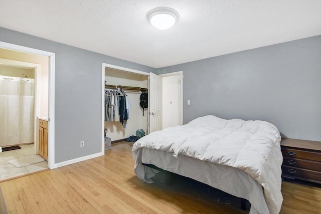 bedroom with light hardwood / wood-style flooring, connected bathroom, and a closet