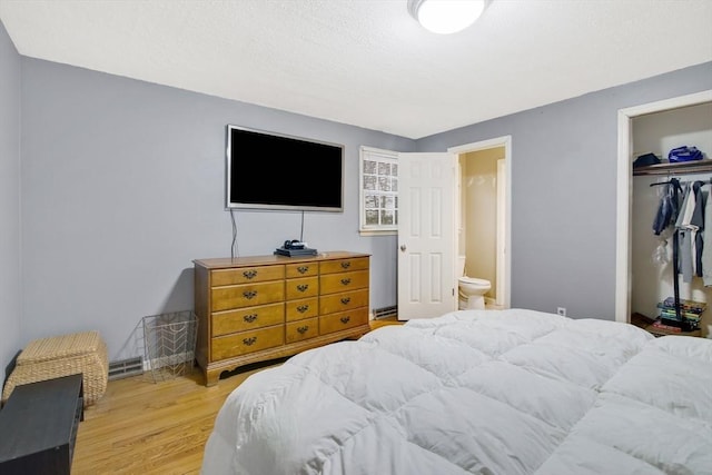 bedroom featuring a spacious closet, light hardwood / wood-style flooring, connected bathroom, and a closet