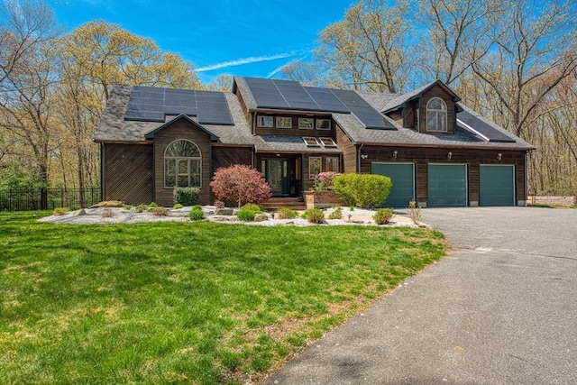 view of front of house with aphalt driveway, a garage, fence, and a front lawn