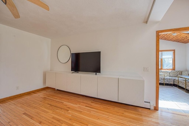 unfurnished living room with a ceiling fan, a textured ceiling, vaulted ceiling, light wood-type flooring, and baseboards