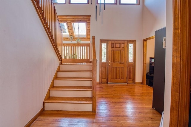 entrance foyer with hardwood / wood-style flooring, baseboards, stairway, and a towering ceiling