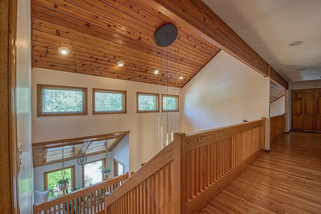 corridor with wood finished floors, beamed ceiling, high vaulted ceiling, recessed lighting, and an upstairs landing