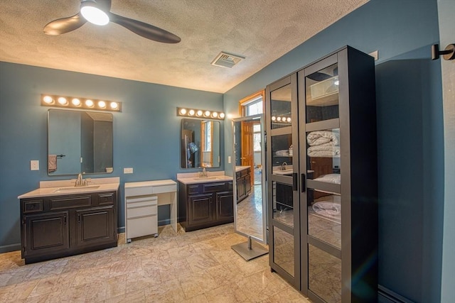 ensuite bathroom with visible vents, two vanities, a sink, and ensuite bath