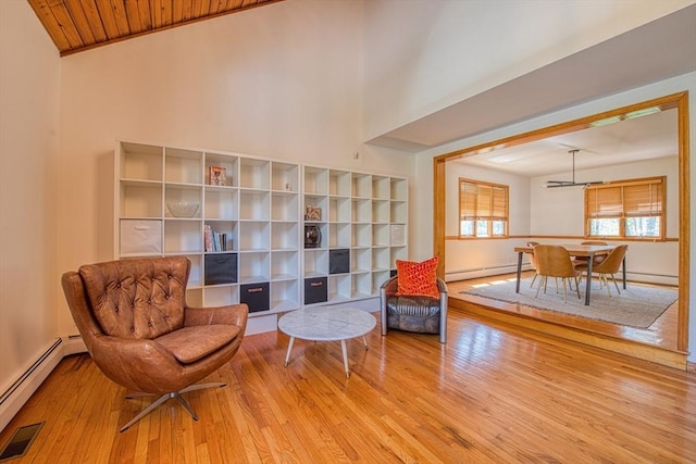 living area with visible vents, baseboard heating, hardwood / wood-style flooring, and a baseboard radiator