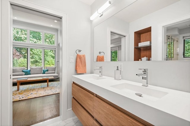 ensuite bathroom with double vanity, ensuite bath, and a sink