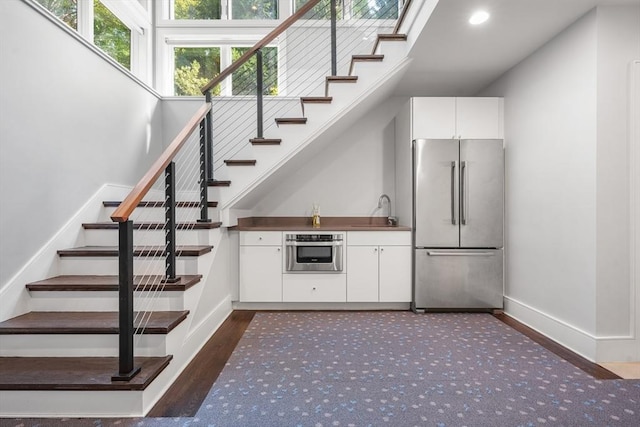 bar with baseboards, dark wood-style floors, stairs, stainless steel appliances, and a sink