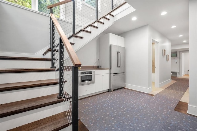 staircase featuring carpet, a skylight, baseboards, and recessed lighting