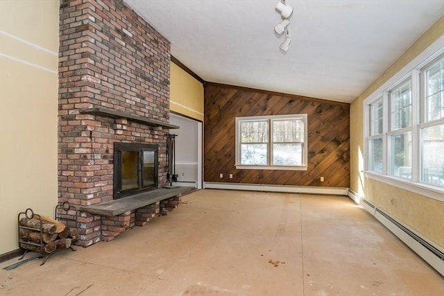 unfurnished living room with track lighting, a baseboard heating unit, a brick fireplace, and wood walls