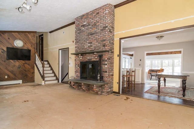 living room with concrete flooring, a fireplace, wooden walls, baseboard heating, and a textured ceiling