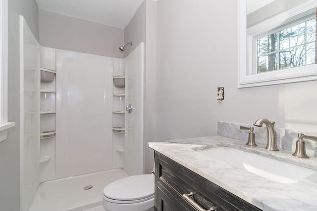 bathroom with walk in shower, vanity, and toilet