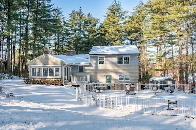 snow covered house with an outbuilding and a deck