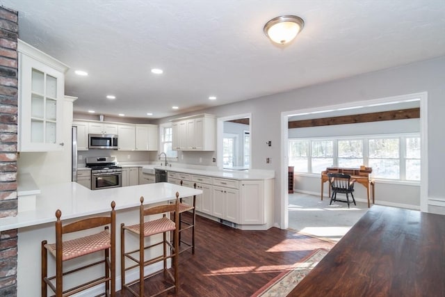 kitchen with white cabinetry, a breakfast bar area, kitchen peninsula, and appliances with stainless steel finishes