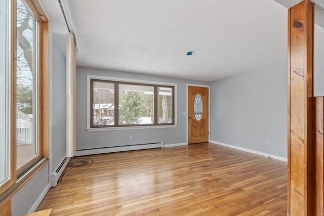 foyer entrance with light wood-type flooring, a baseboard radiator, and baseboards