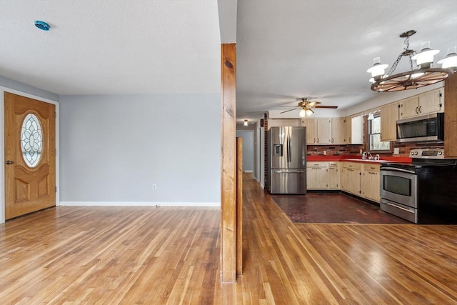 kitchen featuring dark countertops, cream cabinets, appliances with stainless steel finishes, and wood finished floors