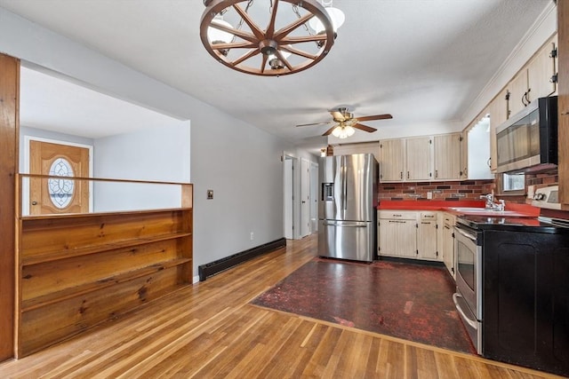 kitchen featuring cream cabinetry, stainless steel appliances, tasteful backsplash, a baseboard heating unit, and wood finished floors