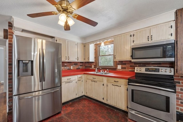 kitchen featuring tasteful backsplash, stainless steel appliances, a textured ceiling, light brown cabinetry, and a sink