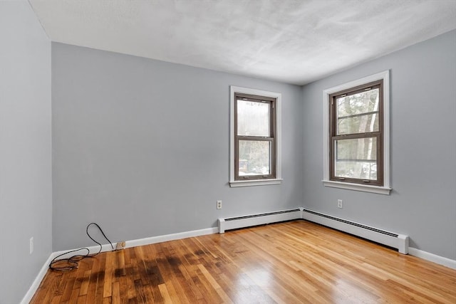 unfurnished room with baseboards, a baseboard heating unit, and wood finished floors