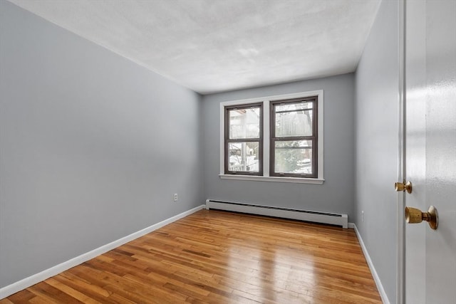 unfurnished room featuring light wood-type flooring, a baseboard radiator, and baseboards