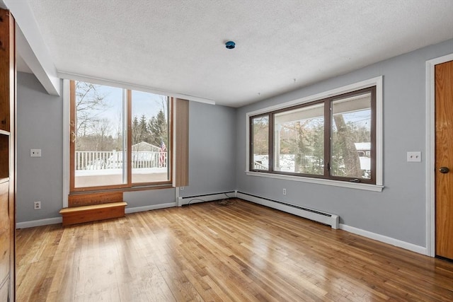 empty room with a textured ceiling, light wood finished floors, and baseboards