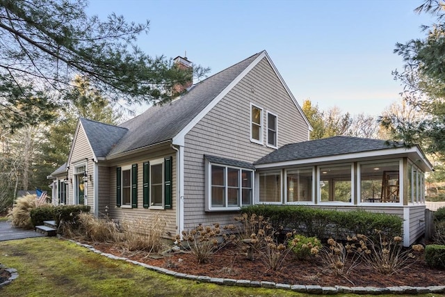 view of side of property with a sunroom and a lawn