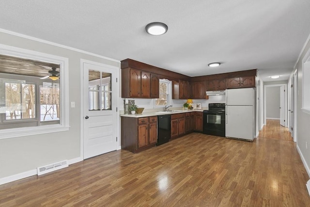 kitchen with hardwood / wood-style flooring, a wealth of natural light, and black appliances