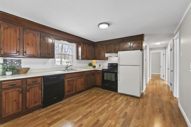 kitchen featuring sink, light hardwood / wood-style flooring, dark brown cabinetry, and black appliances