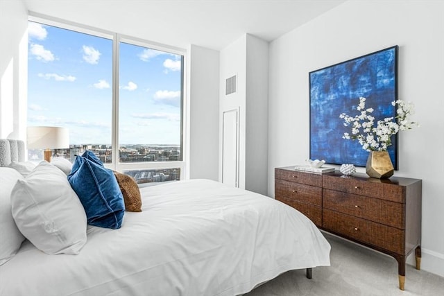 bedroom featuring a wall of windows, carpet, visible vents, and baseboards