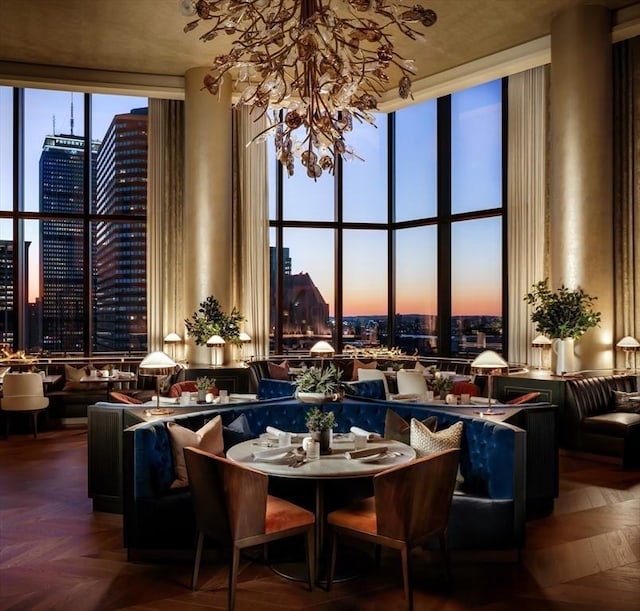 interior space with a high ceiling, a view of city, a chandelier, and a wall of windows