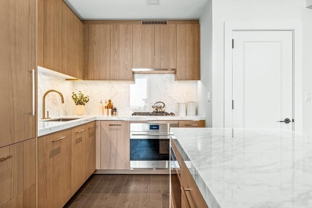 kitchen featuring stainless steel appliances, tasteful backsplash, modern cabinets, and a sink