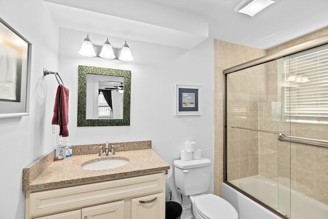 full bathroom with toilet, enclosed tub / shower combo, ceiling fan, and vanity