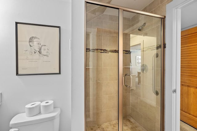 bathroom featuring a shower with shower door and toilet