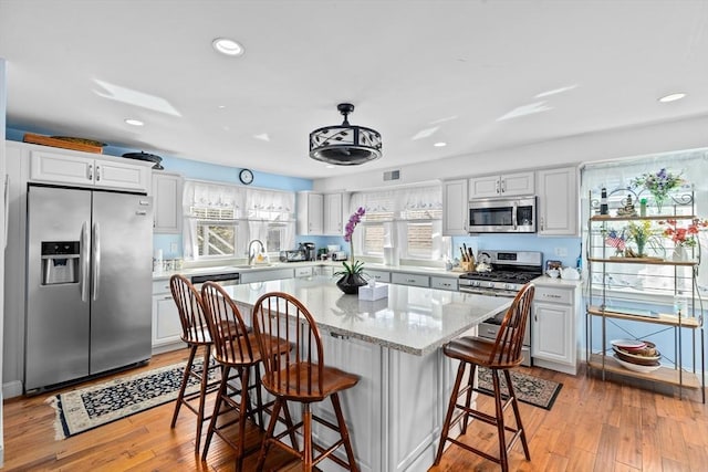 kitchen with stainless steel appliances, light hardwood / wood-style floors, white cabinets, and a center island