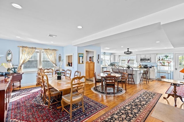 dining room with light wood-type flooring and a healthy amount of sunlight