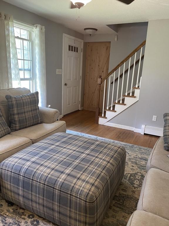 bedroom with baseboards, visible vents, wood finished floors, and a baseboard radiator
