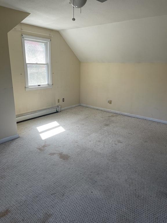 additional living space with baseboards, carpet, lofted ceiling, and a baseboard radiator