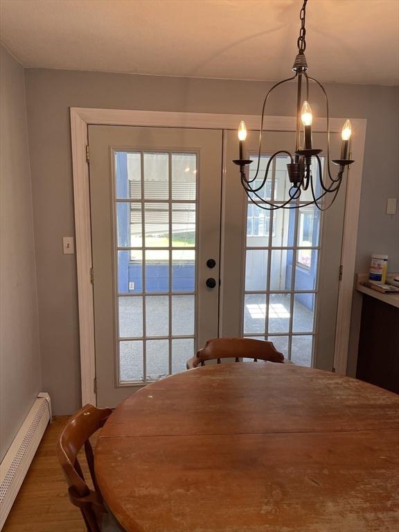 dining room featuring wood finished floors, a chandelier, and baseboard heating