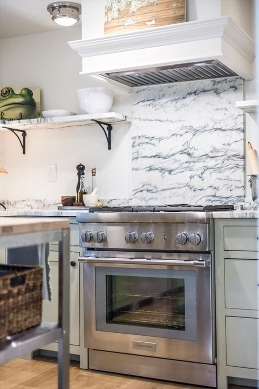 kitchen with gray cabinets, high end stainless steel range, light hardwood / wood-style flooring, and custom range hood