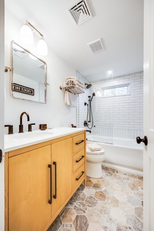 full bathroom featuring toilet, vanity, and tiled shower / bath combo