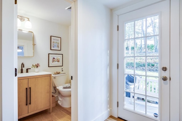 bathroom with wood-type flooring, toilet, and vanity