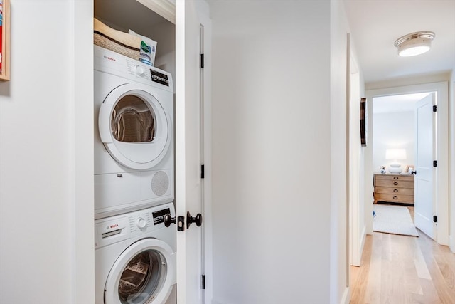 laundry area with light wood-type flooring and stacked washer and dryer