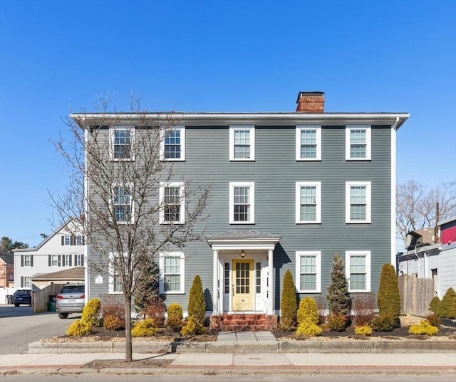 colonial home with fence and a chimney