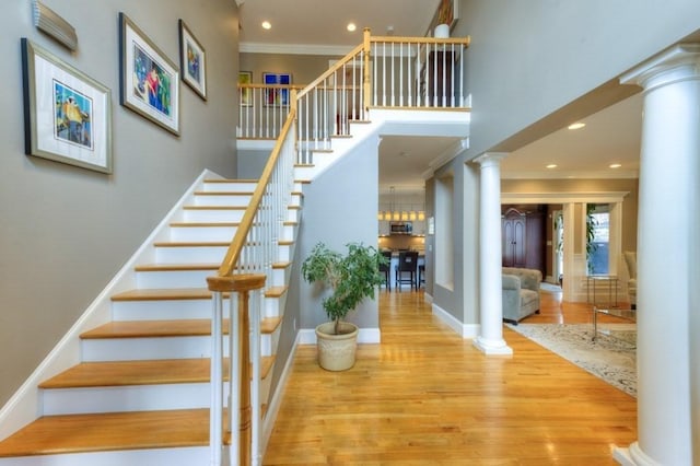 entrance foyer featuring stairway, wood finished floors, ornamental molding, and ornate columns