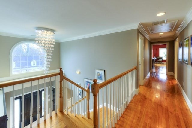 hall with crown molding, attic access, an upstairs landing, wood finished floors, and baseboards