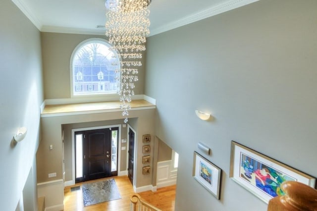 entryway featuring baseboards, ornamental molding, wood finished floors, and an inviting chandelier