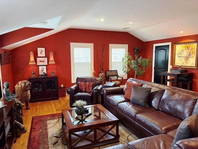 living area featuring lofted ceiling, light wood-type flooring, and visible vents