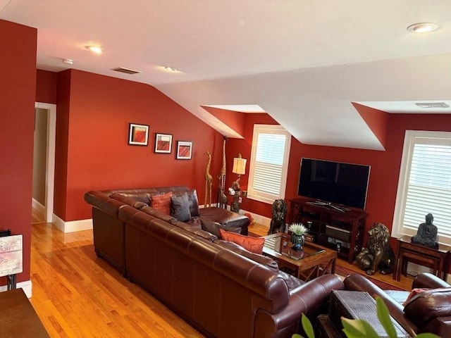 living room featuring lofted ceiling, light wood finished floors, baseboards, and visible vents