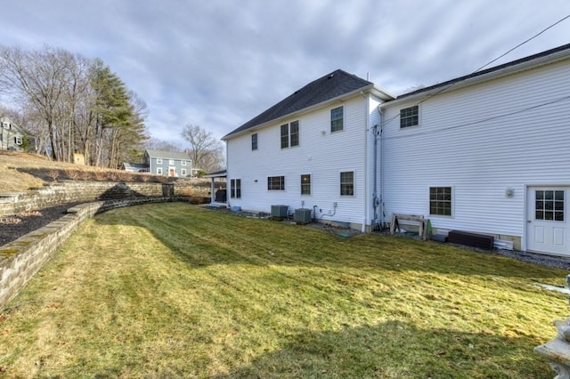 back of property with central AC unit and a lawn