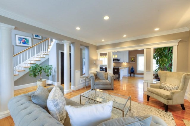 living room featuring ornamental molding, decorative columns, and light wood-style floors