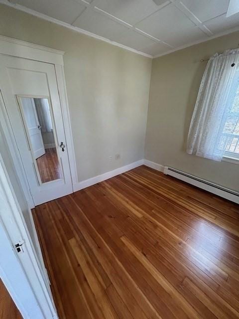 unfurnished room with a baseboard radiator, crown molding, baseboards, and wood finished floors