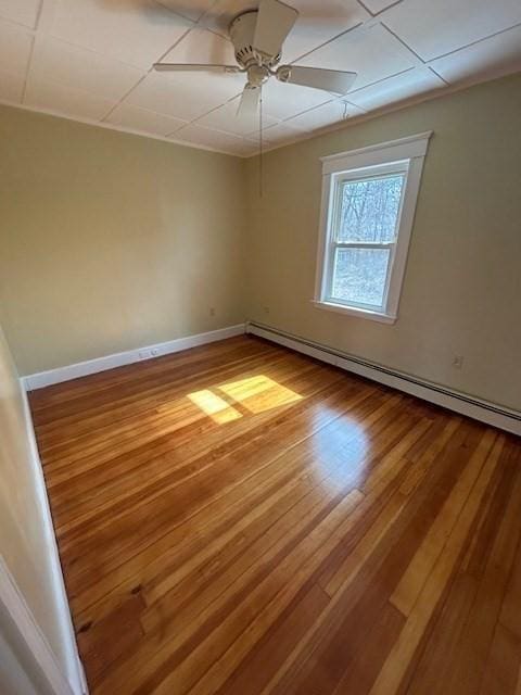 empty room with hardwood / wood-style flooring, a ceiling fan, baseboards, and a baseboard radiator